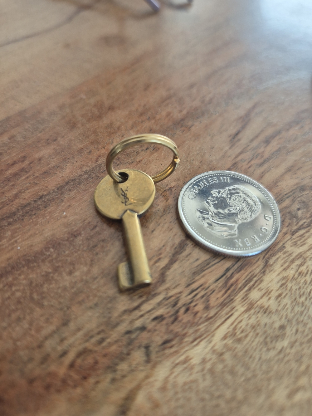 Small metal key and coin on wood